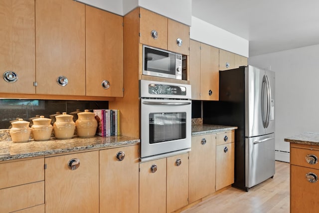 1700 Arthur Ave, Missoula, MT 59801 - kitchen with stainless steel appliances, light wood finished floors, light stone counters, and a baseboard radiator