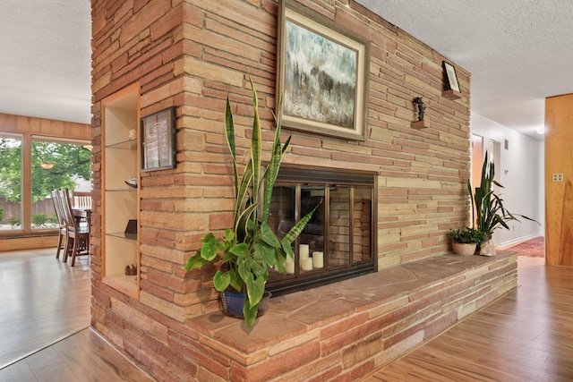 1700 Arthur Ave, Missoula, MT 59801 - unfurnished living room with a textured ceiling, wood finished floors, and a glass covered fireplace
