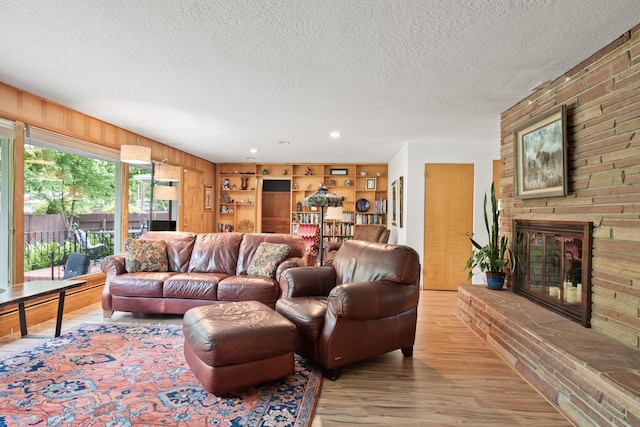 1700 Arthur Ave, Missoula, MT 59801 - living room with a textured ceiling, light wood finished floors, a fireplace, and wooden walls