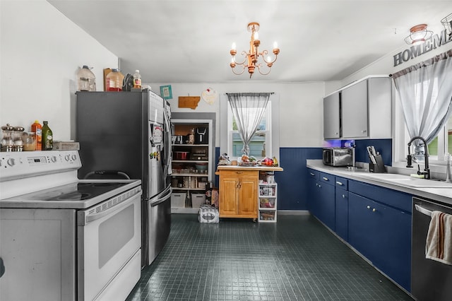 1126 4th Ave S, Great Falls, MT 59405 - kitchen with appliances with stainless steel finishes, a chandelier, blue cabinetry, healthy amount of natural light, and wainscoting