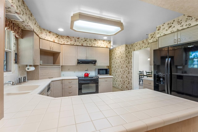 1229 Old Orchard Rd, Missoula, MT 59802 - kitchen with stove, stainless steel microwave, wallpapered walls, under cabinet range hood, and black fridge