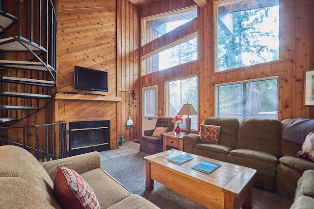 118 Ptarmigan Blvd Unit 118, Whitefish, MT 59937 - living area with wooden walls, a towering ceiling, a fireplace with flush hearth, stairs, and tile patterned floors