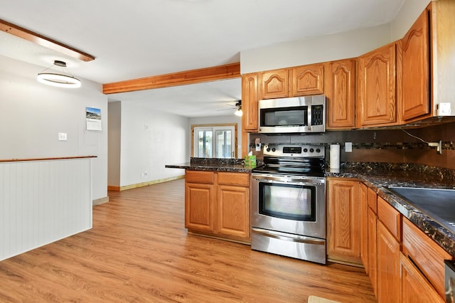 3121 6th Ave S, Great Falls, MT 59405 - kitchen featuring stainless steel appliances, a peninsula, light wood-type flooring, brown cabinetry, and beam ceiling