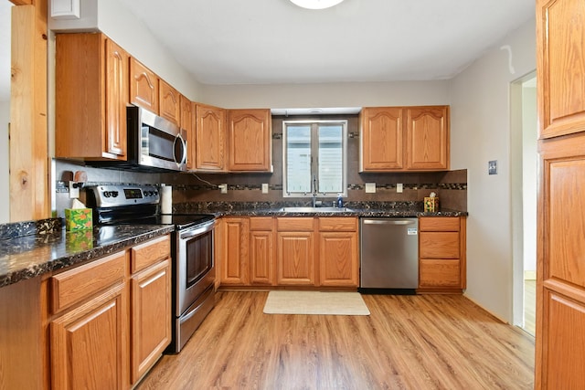 3121 6th Ave S, Great Falls, MT 59405 - kitchen featuring stainless steel appliances, light wood-type flooring, decorative backsplash, and dark stone counters