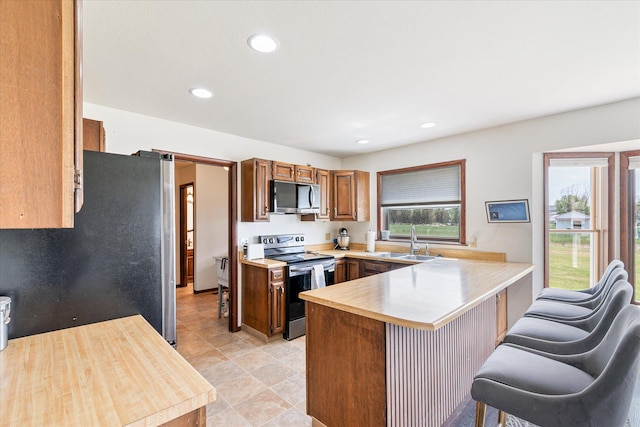 3446 Tizer Dr, Helena, MT 59602 - kitchen featuring appliances with stainless steel finishes, a peninsula, a kitchen breakfast bar, recessed lighting, and brown cabinetry