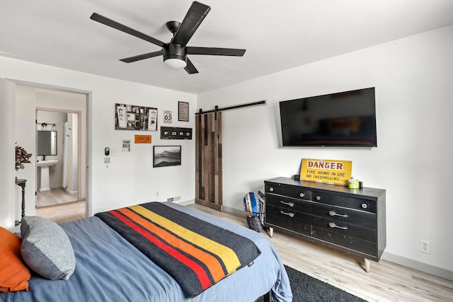 223 12th St N, Great Falls, MT 59401 - bedroom with a barn door, light wood-type flooring, ceiling fan, and connected bathroom