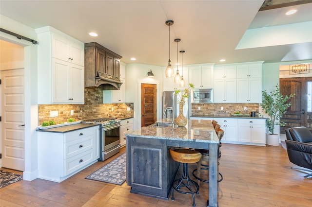 128 Antler Peak Ln, Kalispell, MT 59901 - kitchen with stainless steel appliances, a breakfast bar area, light wood-type flooring, backsplash, and white cabinets