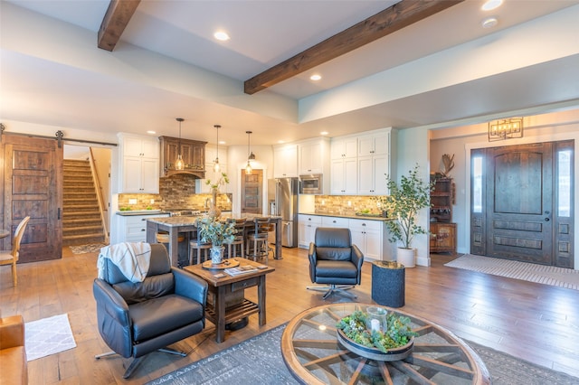 128 Antler Peak Ln, Kalispell, MT 59901 - living area featuring beam ceiling, light wood-style flooring, recessed lighting, a barn door, and stairway