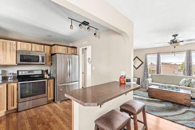 1237 Park Garden Rd, Great Falls, MT 59404 - kitchen featuring stainless steel appliances, dark countertops, wood finished floors, and a kitchen breakfast bar