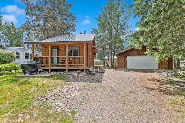 34045 Redgate Dr, Bigfork, MT 59911 - rustic home featuring a garage, a metal roof, an outbuilding, and a wooden deck