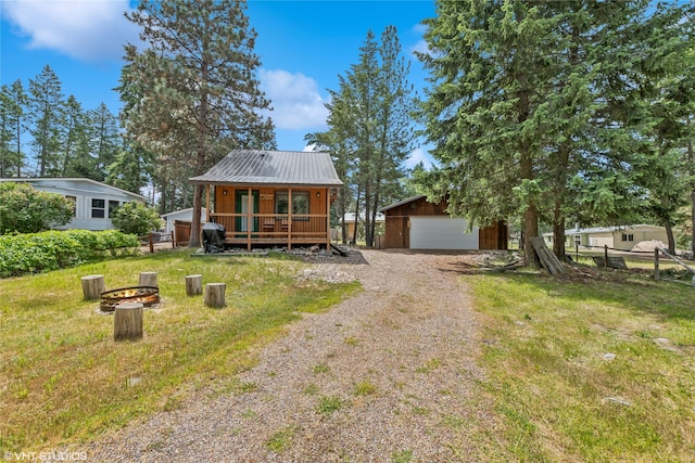 34045 Redgate Dr, Bigfork, MT 59911 - view of front facade with an outbuilding, a metal roof, an outdoor fire pit, a garage, and a deck