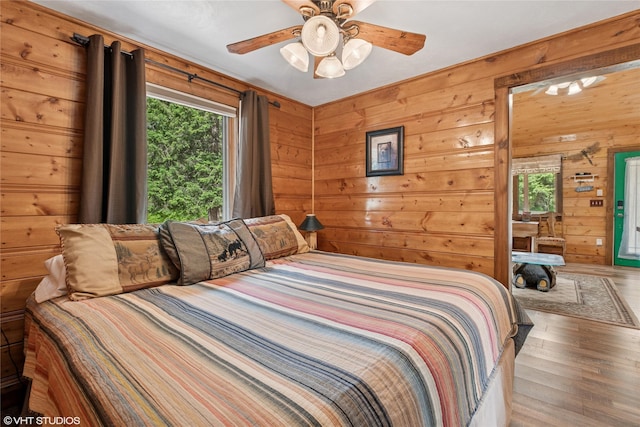 34045 Redgate Dr, Bigfork, MT 59911 - bedroom with multiple windows, wood finished floors, wood walls, and ceiling fan
