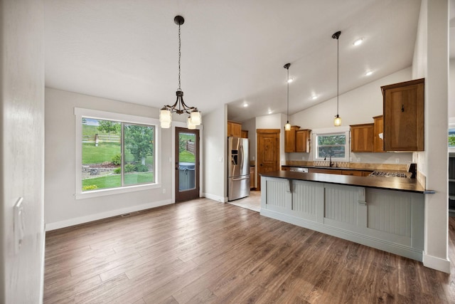 150 Swede Trl, Kalispell, MT 59901 - kitchen with stainless steel fridge with ice dispenser, dark countertops, brown cabinets, a chandelier, and wood finished floors