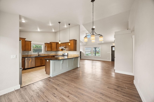 150 Swede Trl, Kalispell, MT 59901 - kitchen with appliances with stainless steel finishes, open floor plan, brown cabinets, light wood-style floors, and a chandelier