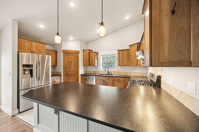 150 Swede Trl, Kalispell, MT 59901 - kitchen with stainless steel appliances, under cabinet range hood, a peninsula, brown cabinets, and dark countertops