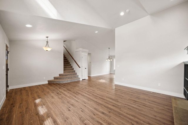 150 Swede Trl, Kalispell, MT 59901 - unfurnished living room featuring vaulted ceiling, stairway, wood finished floors, recessed lighting, and a chandelier