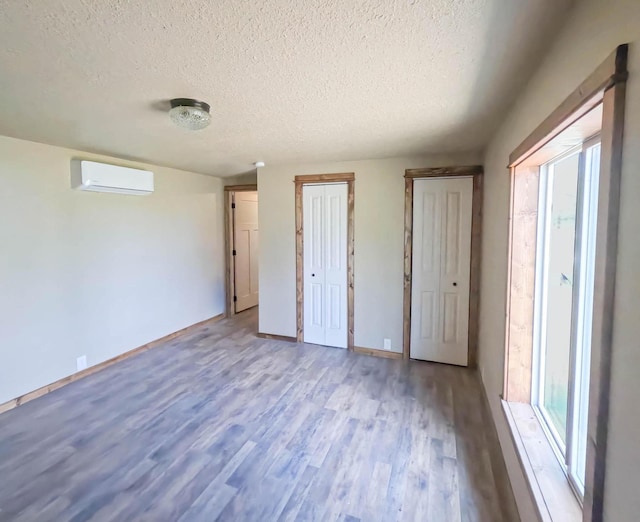 36240 Felsman St, Pablo, MT 59855 - unfurnished bedroom with a wall unit AC, a textured ceiling, wood finished floors, and a closet