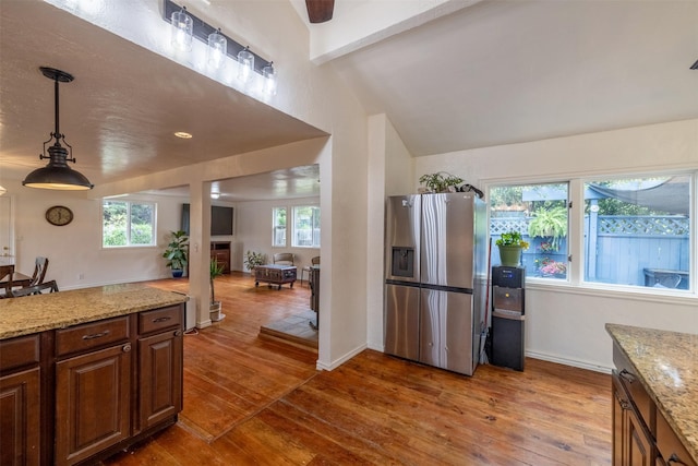 3422 Rimini Rd, Helena, MT 59601 - kitchen featuring stainless steel fridge with ice dispenser, wood-type flooring, light stone countertops, hanging light fixtures, and vaulted ceiling