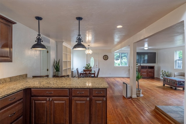 3422 Rimini Rd, Helena, MT 59601 - kitchen with open floor plan, a peninsula, wood finished floors, hanging light fixtures, and light stone countertops