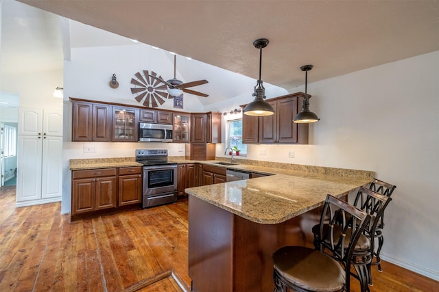 3422 Rimini Rd, Helena, MT 59601 - kitchen with stainless steel appliances, a peninsula, hardwood / wood-style flooring, a kitchen breakfast bar, and glass insert cabinets