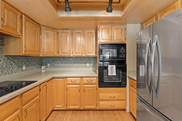 7 Eagle Bend Dr, Bigfork, MT 59911 - kitchen with black appliances, a raised ceiling, light wood-style flooring, and backsplash