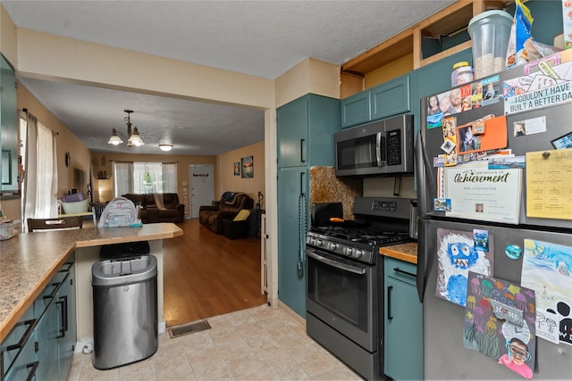 521 2nd Ave SW, Great Falls, MT 59404 - kitchen with stainless steel appliances, green cabinets, a chandelier, open floor plan, and pendant lighting