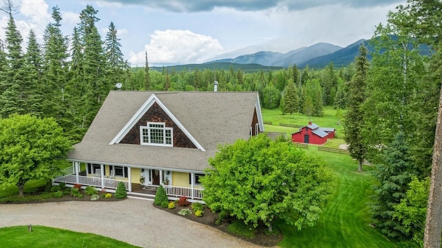 420 Little Creek Ln, Whitefish, MT 59937 - view of front of home with covered porch, a mountain view, a front yard, and a view of trees