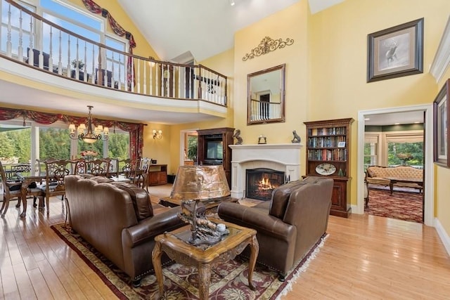 420 Little Creek Ln, Whitefish, MT 59937 - living room with a lit fireplace, high vaulted ceiling, light wood finished floors, and a chandelier