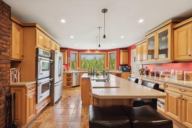 420 Little Creek Ln, Whitefish, MT 59937 - kitchen with appliances with stainless steel finishes, an island with sink, recessed lighting, a kitchen breakfast bar, and glass insert cabinets