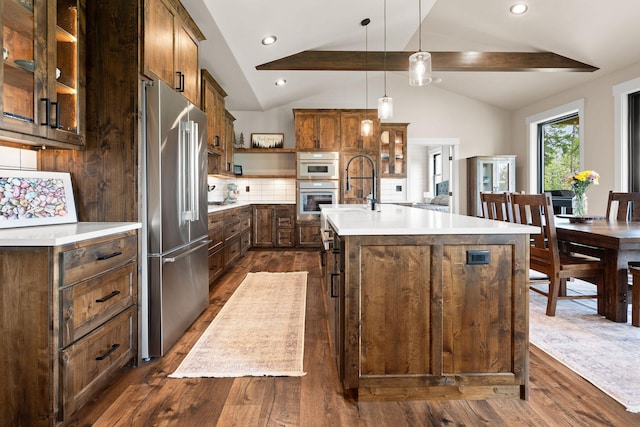 331 Deer Creek Rd, Somers, MT 59932 - kitchen with stainless steel appliances, dark wood-style floors, light countertops, a center island with sink, and glass insert cabinets