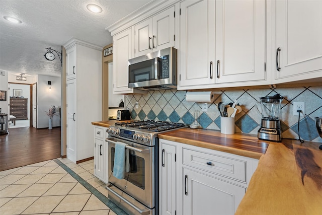 4786 Hereford Ln, Stevensville, MT 59870 - kitchen featuring stainless steel appliances, wooden counters, a textured ceiling, light tile patterned floors, and white cabinets