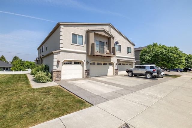 310 Barney St Unit B, Helena, MT 59602 - view of front facade featuring driveway, a balcony, a garage, stone siding, and a front yard
