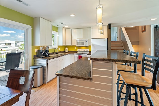 3782 E Riggs St, East Helena, MT 59635 - kitchen featuring white appliances, a center island, light wood-type flooring, a breakfast bar, and recessed lighting