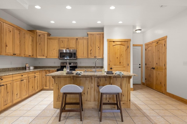 396 N Juniper Bay Rd Unit 15, Somers, MT 59932 - kitchen featuring stainless steel appliances, a kitchen breakfast bar, an island with sink, light stone countertops, and recessed lighting