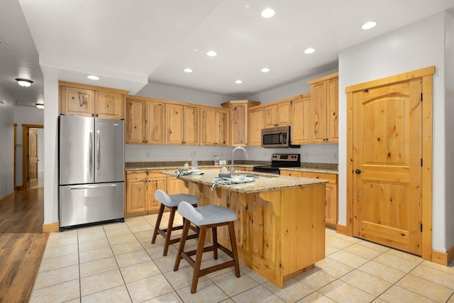 396 N Juniper Bay Rd Unit 15, Somers, MT 59932 - kitchen with stainless steel appliances, recessed lighting, a kitchen island with sink, light stone counters, and light tile patterned floors