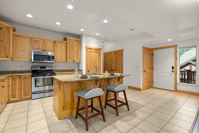 396 N Juniper Bay Rd Unit 15, Somers, MT 59932 - kitchen featuring appliances with stainless steel finishes, light tile patterned flooring, recessed lighting, a kitchen island with sink, and light stone counters