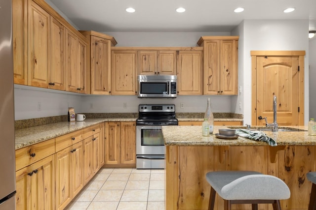 396 N Juniper Bay Rd Unit 15, Somers, MT 59932 - kitchen with stainless steel appliances, a breakfast bar, light stone counters, light tile patterned flooring, and recessed lighting