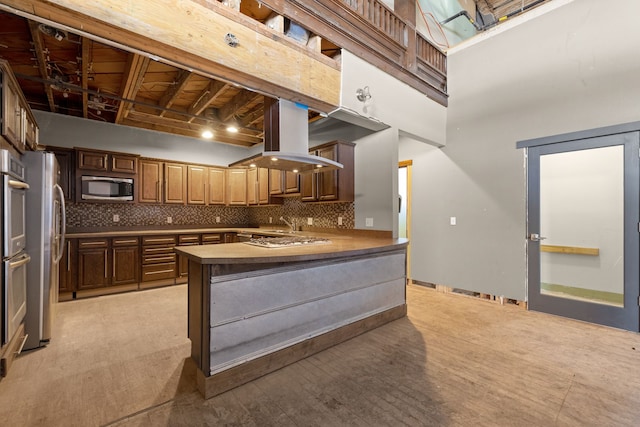 300 2nd St E Unit 2, Whitefish, MT 59937 - kitchen featuring appliances with stainless steel finishes, tasteful backsplash, a peninsula, a towering ceiling, and light wood finished floors