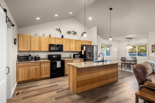 546 Sparrow Rd, Kalispell, MT 59901 - kitchen with black appliances, high vaulted ceiling, light wood finished floors, a center island with sink, and light stone counters