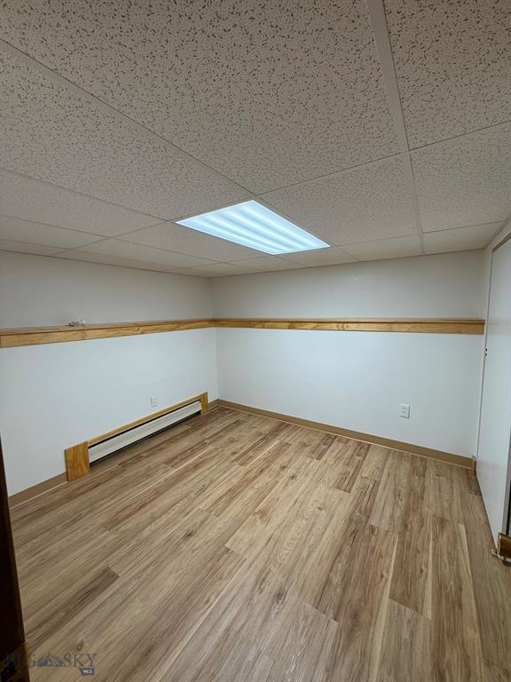2625 George St, Butte, MT 59701 - spare room featuring a baseboard radiator, a drop ceiling, and wood finished floors