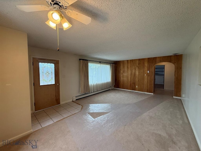 2625 George St, Butte, MT 59701 - empty room with baseboard heating, healthy amount of natural light, a textured ceiling, carpet floors, and arched walkways