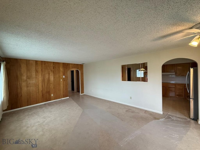 2625 George St, Butte, MT 59701 - unfurnished room featuring arched walkways, ceiling fan, wooden walls, light carpet, and a textured ceiling