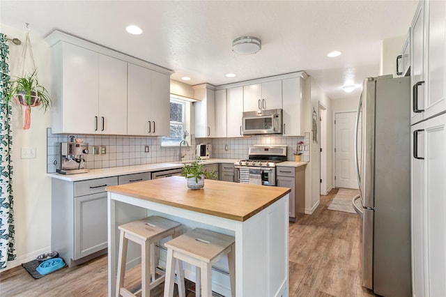 1346 Lilly Ct, Missoula, MT 59802 - kitchen featuring appliances with stainless steel finishes, wood counters, light wood-type flooring, tasteful backsplash, and recessed lighting