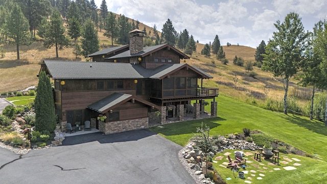 349 Harlan Creek Rd, Hamilton, MT 59840 - view of front of home featuring stone siding, driveway, a front lawn, a sunroom, and a chimney