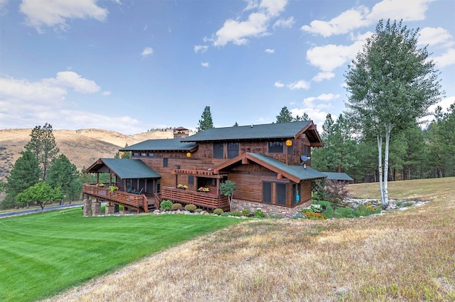 349 Harlan Creek Rd, Hamilton, MT 59840 - rear view of house with a lawn, a chimney, a deck with mountain view, and stone siding