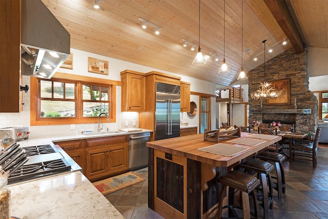 349 Harlan Creek Rd, Hamilton, MT 59840 - kitchen with appliances with stainless steel finishes, wall chimney exhaust hood, butcher block counters, decorative backsplash, and a kitchen island