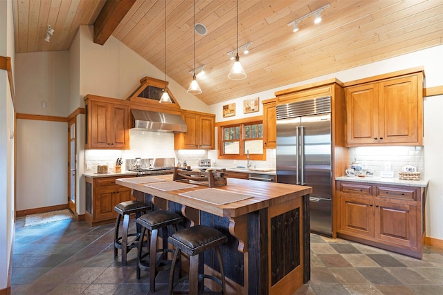 349 Harlan Creek Rd, Hamilton, MT 59840 - kitchen featuring stainless steel built in refrigerator, wall chimney exhaust hood, wood counters, rail lighting, and a kitchen island