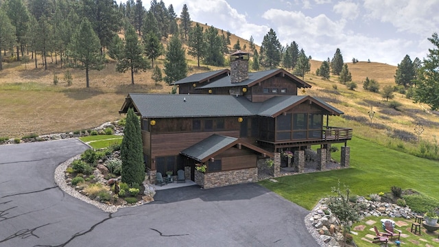 349 Harlan Creek Rd, Hamilton, MT 59840 - view of front facade with driveway, stone siding, a sunroom, a front yard, and a chimney