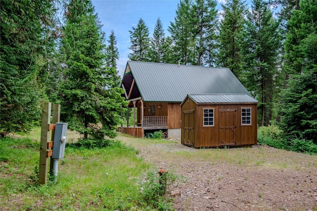 716 Kootenai River Rd, Troy, MT 59935 - view of front of house with a metal roof, a storage shed, a porch, and driveway