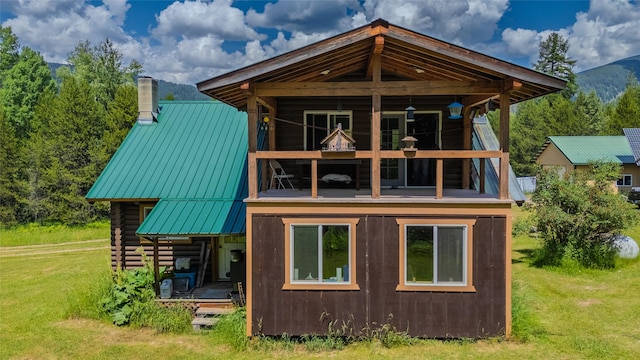 17 Twenty Peak Gulch Ln, Trout Creek, MT 59874 - back of house with a lawn, a chimney, a metal roof, a standing seam roof, and a balcony